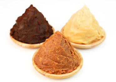 「赤味噌・淡色味噌・白味噌の3種類を木皿に盛り付けた写真。色の違いは発酵期間と風味の特徴を示し、日本料理に合わせた使い分けが可能。」