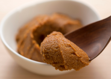 「木製スプーンですくった味噌。発酵によって旨味と栄養価が高まった日本の伝統的な調味料。」