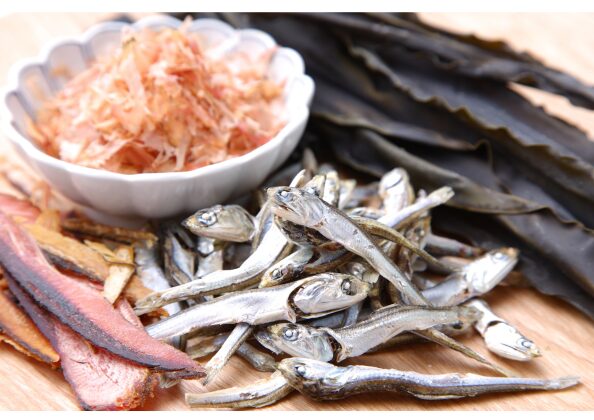 昆布・鰹節・煮干しなど、日本の伝統的なだし素材が並ぶ木製の調理台。味噌汁や和食のうま味の基本となる食材。