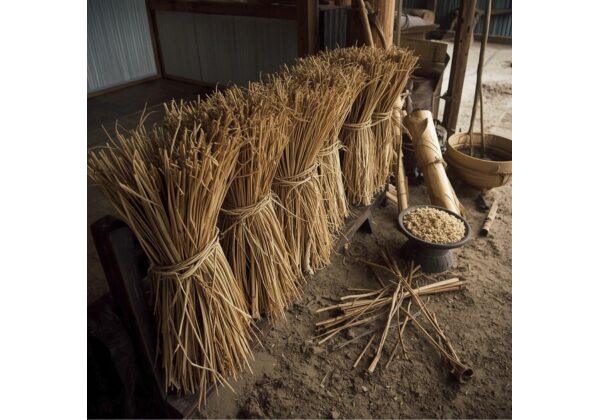乾燥した植物の茎を束ねて縄状にした芋がら縄の再現。木の台に立てかけられ、周囲には穀物や農具が置かれた素朴な作業場の風景。