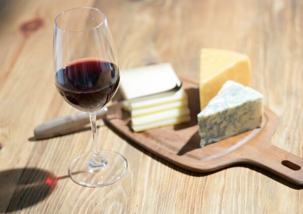 「赤ワインと3種のチーズが並ぶ木製ボード。発酵食品の保存性と栄養価を象徴する食卓風景。」