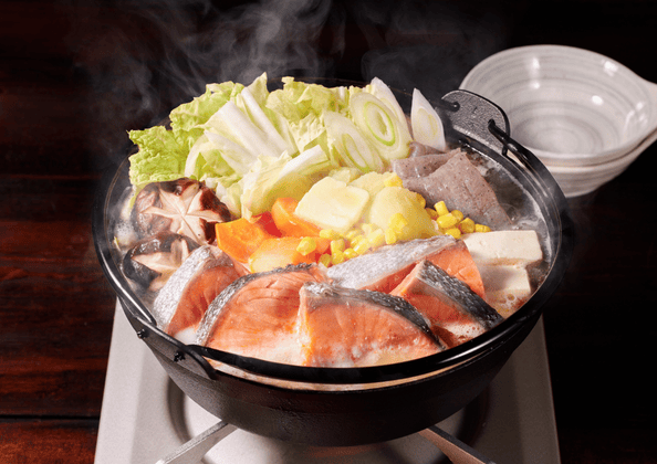 鮭、豆腐、野菜がたっぷり入った石狩鍋。味噌ベースの熱々の鍋料理で湯気が立ち上る