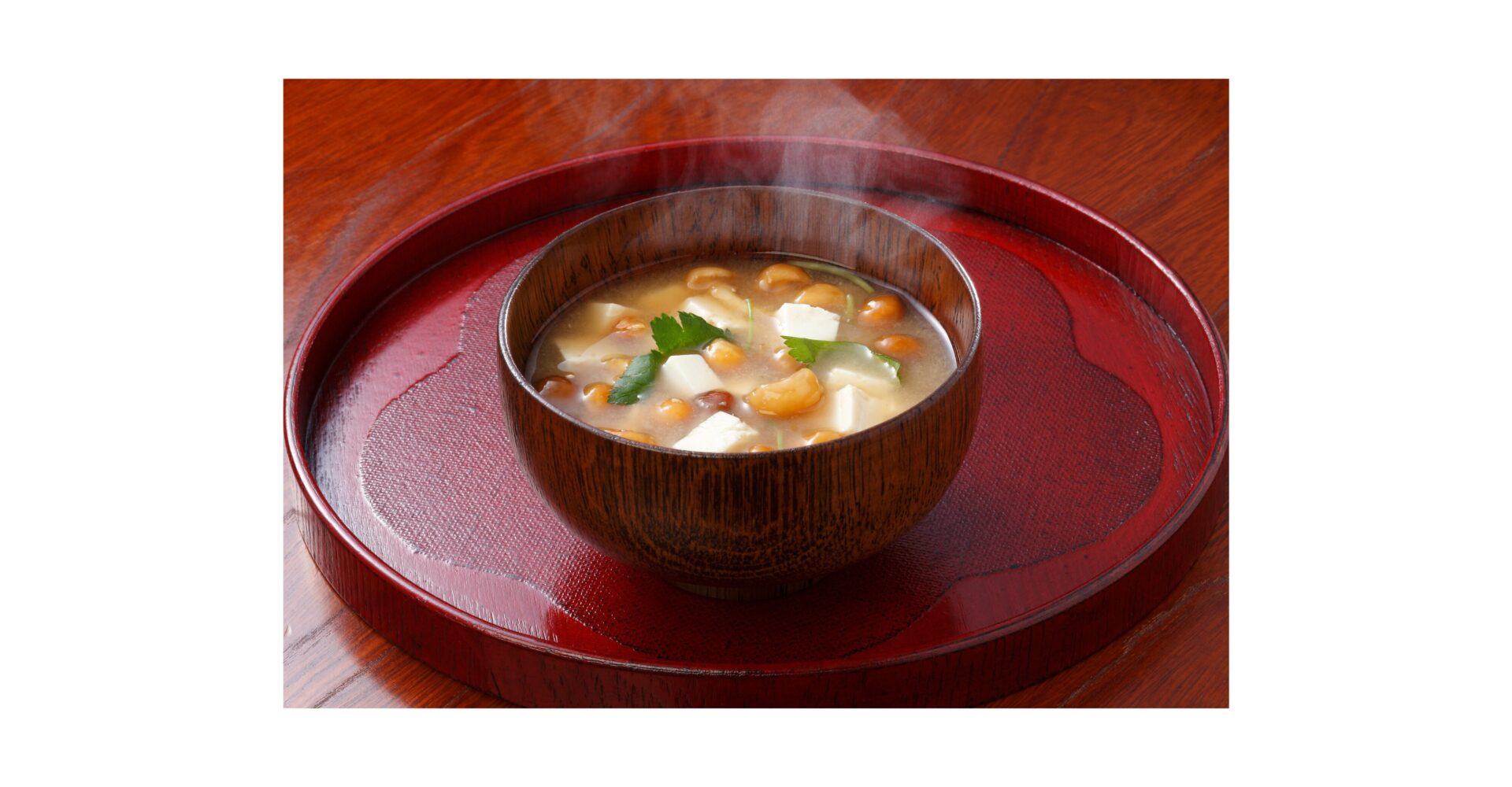 「湯気が立ちのぼる木椀の味噌汁｜豆腐と青菜が入った家庭の味」