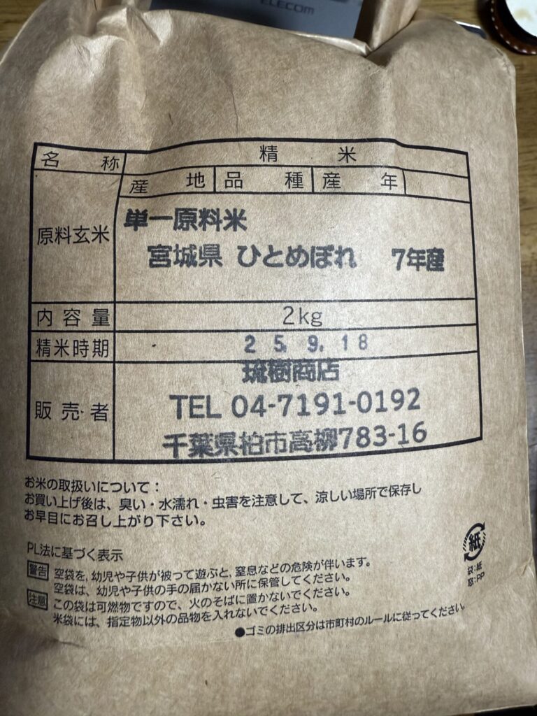「宮城県産ひとめぼれ(令和7年産)の精米2kgが入った茶色の紙袋。袋には産地、品種、精米日、販売者情報、お米の保存方法やPL法に基づく注意書きが印刷されている。」